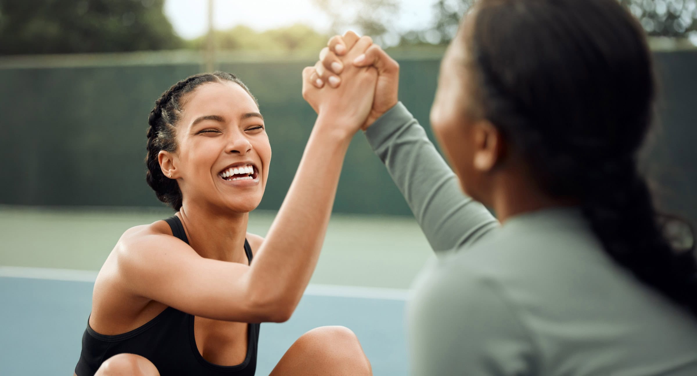 Athletic woman celebrating victory with high-five at outdoor sports court.