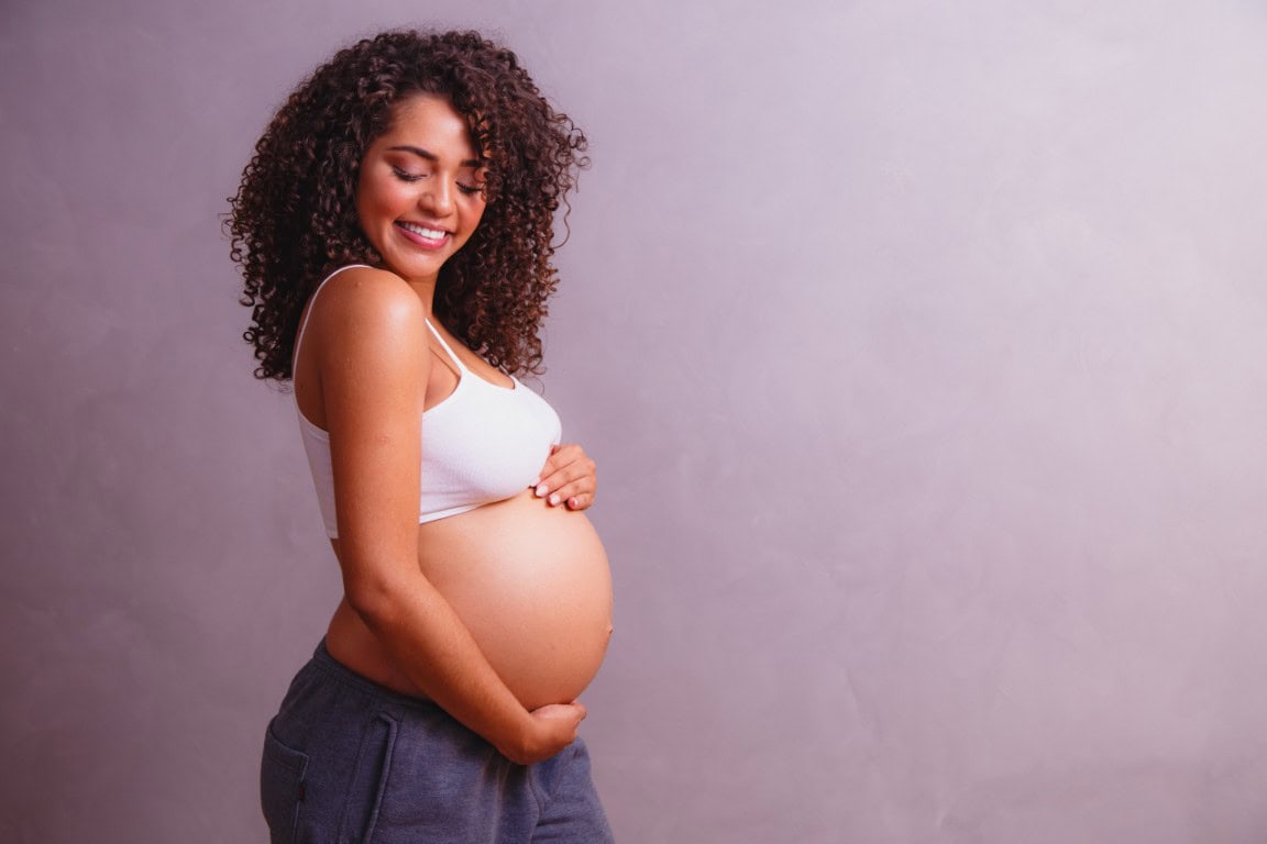Pregnant woman holding her belly, promoting maternity wellness and hydration IV therapy at The Wellness Drip INC.