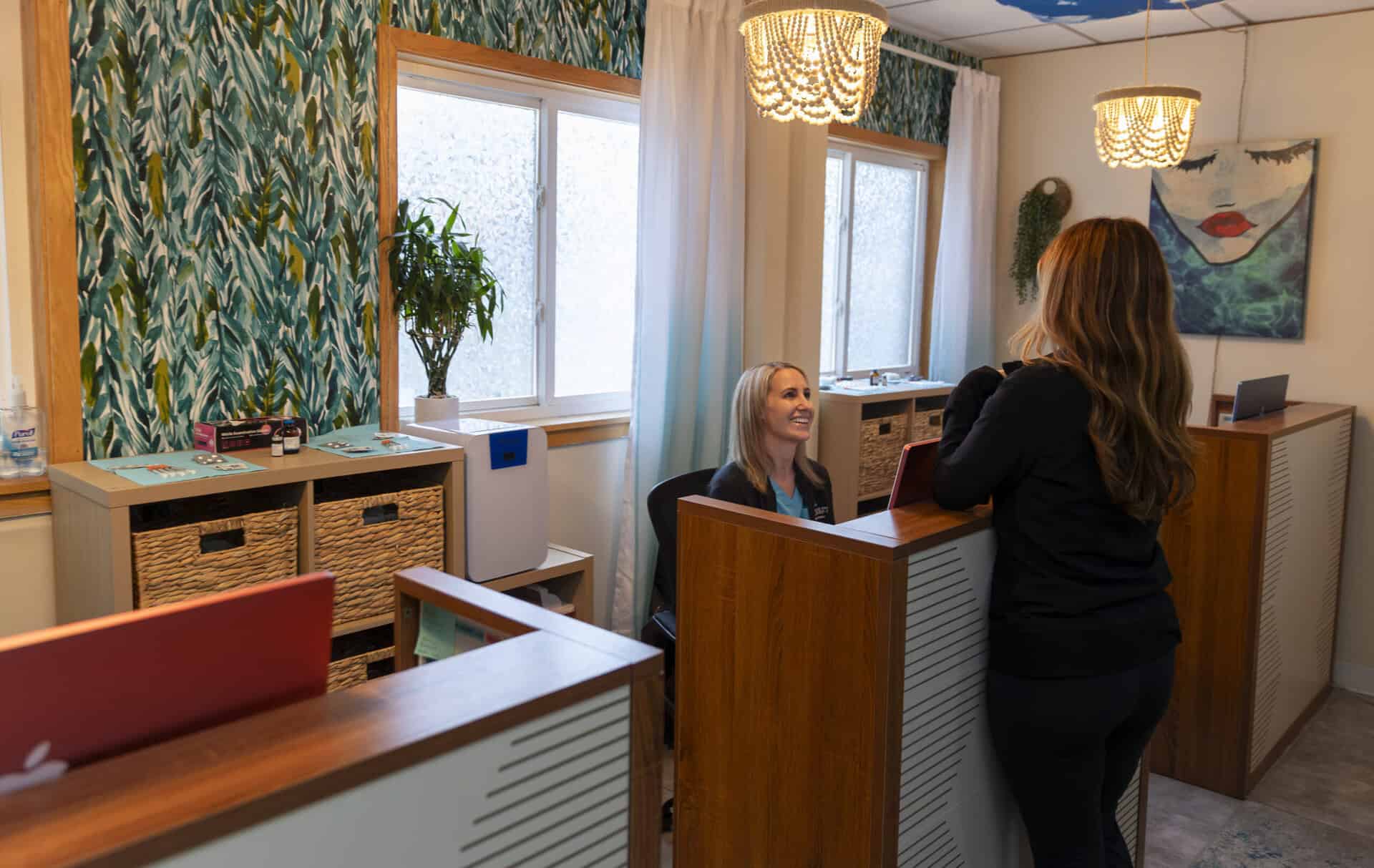 A friendly receptionist at The Wellness Drip INC assisting a client in a cozy wellness clinic in MA, offering ketamine therapy, weight loss, and wellness services.