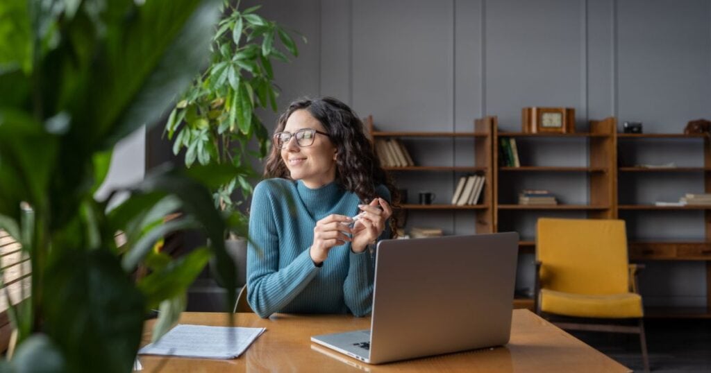 Relaxed woman in a wellness clinic working on a laptop, promoting mental health and holistic wellness services.