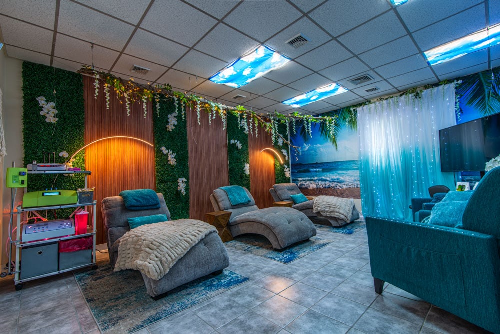 Relaxing wellness lounge with soothing ocean views, tropical decor, and comfortable reclining chairs at The Wellness Drip Inc, MA wellness clinic offering IV therapy and mental health treatments.