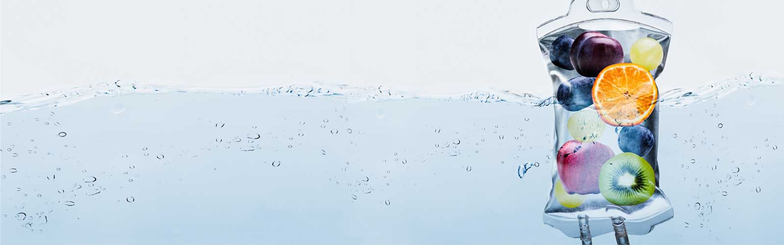 Fresh fruit-infused IV therapy bag with blueberries, kiwi, apple, orange, and grapes, offering wellness and vitamin infusion services at a MA wellness clinic.