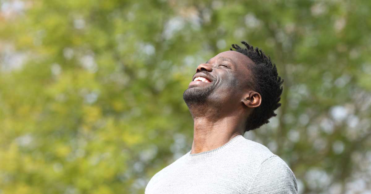 Man smiling outdoors enjoying wellness and mental health benefits.