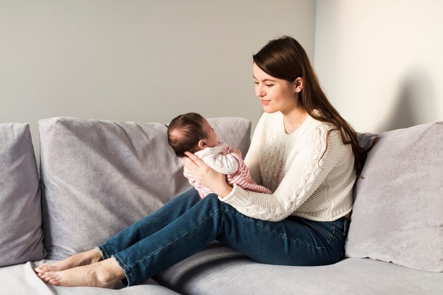 Beautiful mother holding her newborn baby, interior shot in a wellness clinic setting, emphasizing health and wellness services.