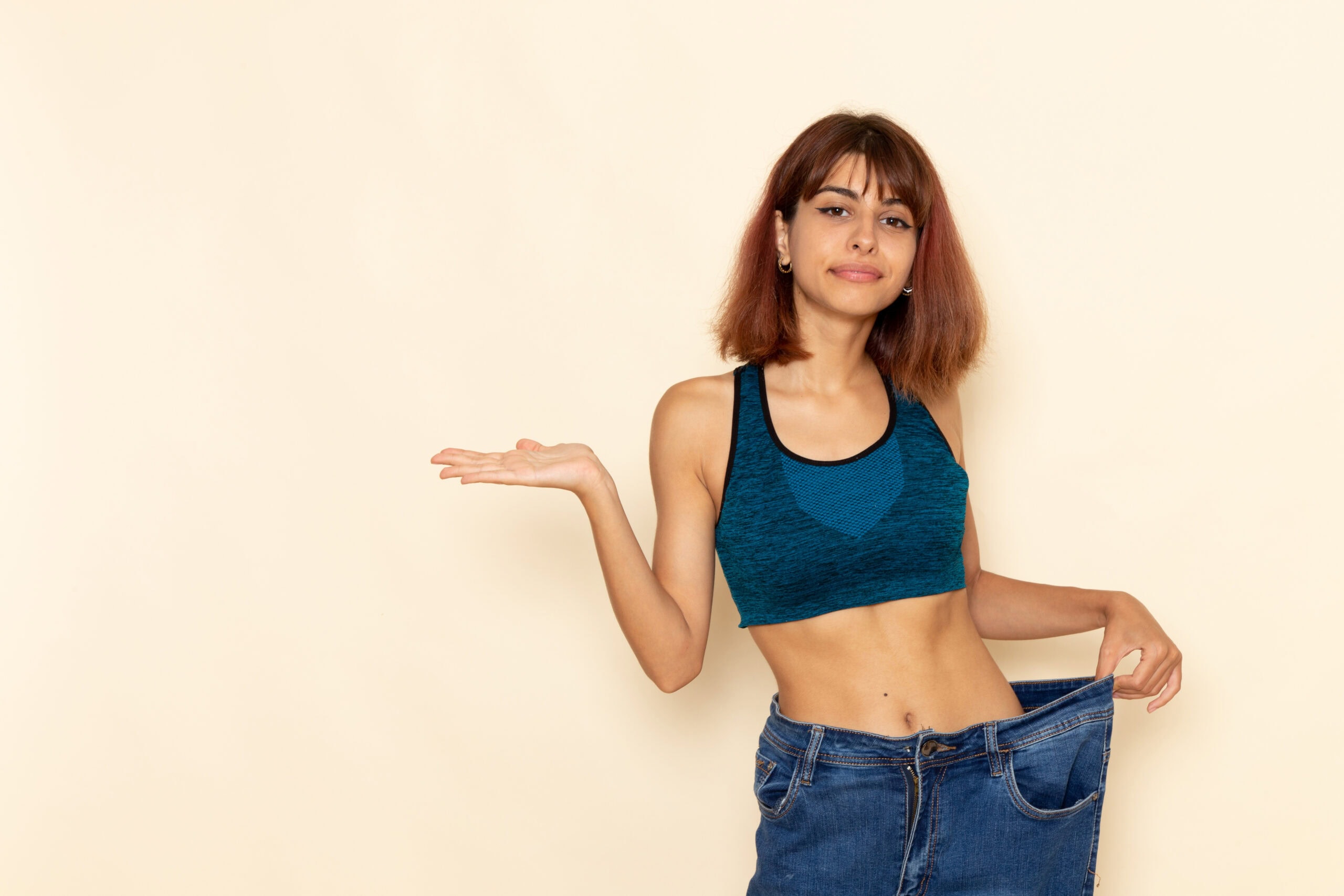 Weight loss transformation with loose jeans, woman showing her smaller waist after healthy wellness and weight management programs at The Wellness Drip INC in MA.