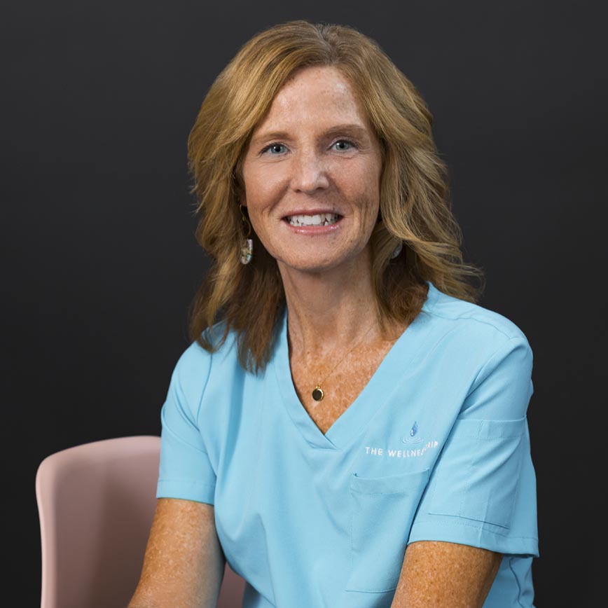 Chrissy in blue medical scrubs at wellness clinic MA emphasizing ketamine therapy, weight loss, NAD+ infusions, ozone therapy, chronic pain relief.