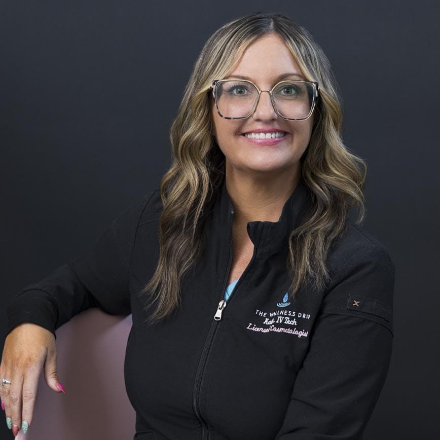 Katie from Wellness Drip - wearing glasses and wellness clinic jacket, promoting ketamine therapy and IV vitamin infusions at The Wellness Drip, MA.