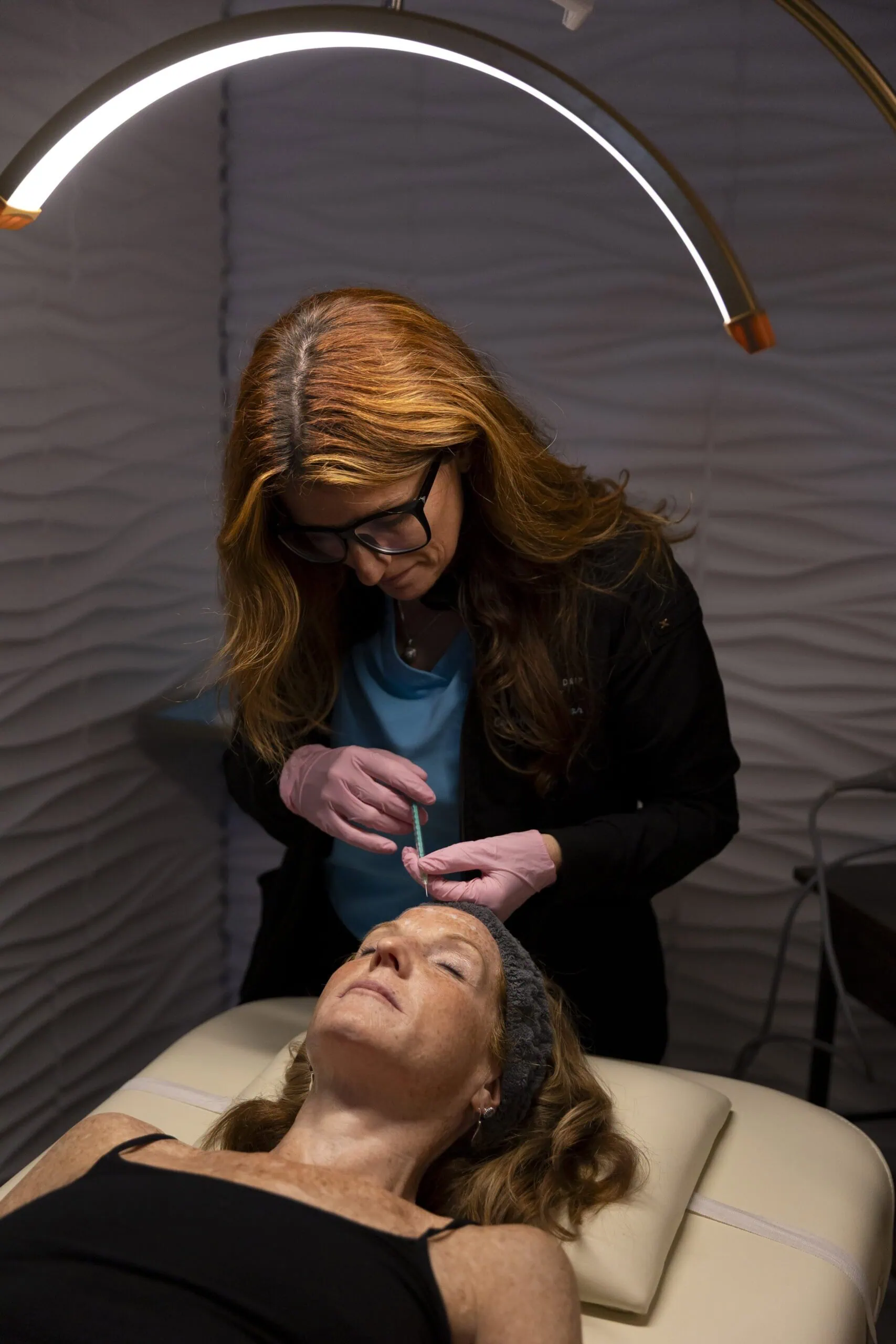 Therapist administering injection to mature woman during wellness treatment at The Wellness Drip INC, MA.