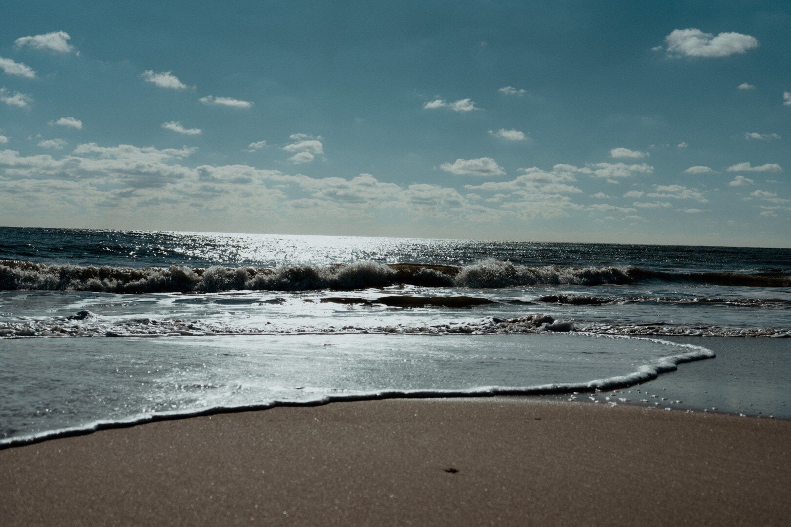 A calming image of ocean waves gently hitting the sandy shore, highlighting wellness and relaxation services offered by The Wellness Drip INC for health and vitality.