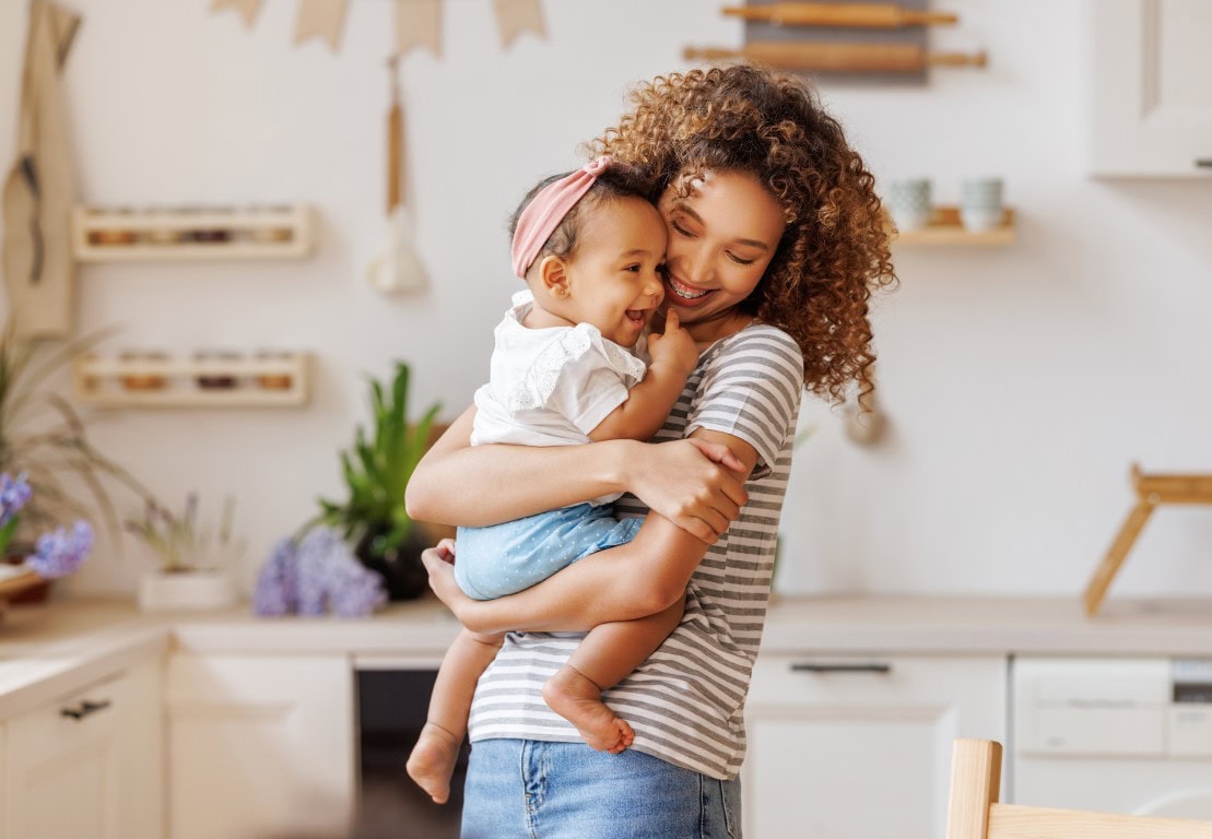 A happy mother with her smiling young daughter enjoying quality time together in a cozy, modern kitchen setting.