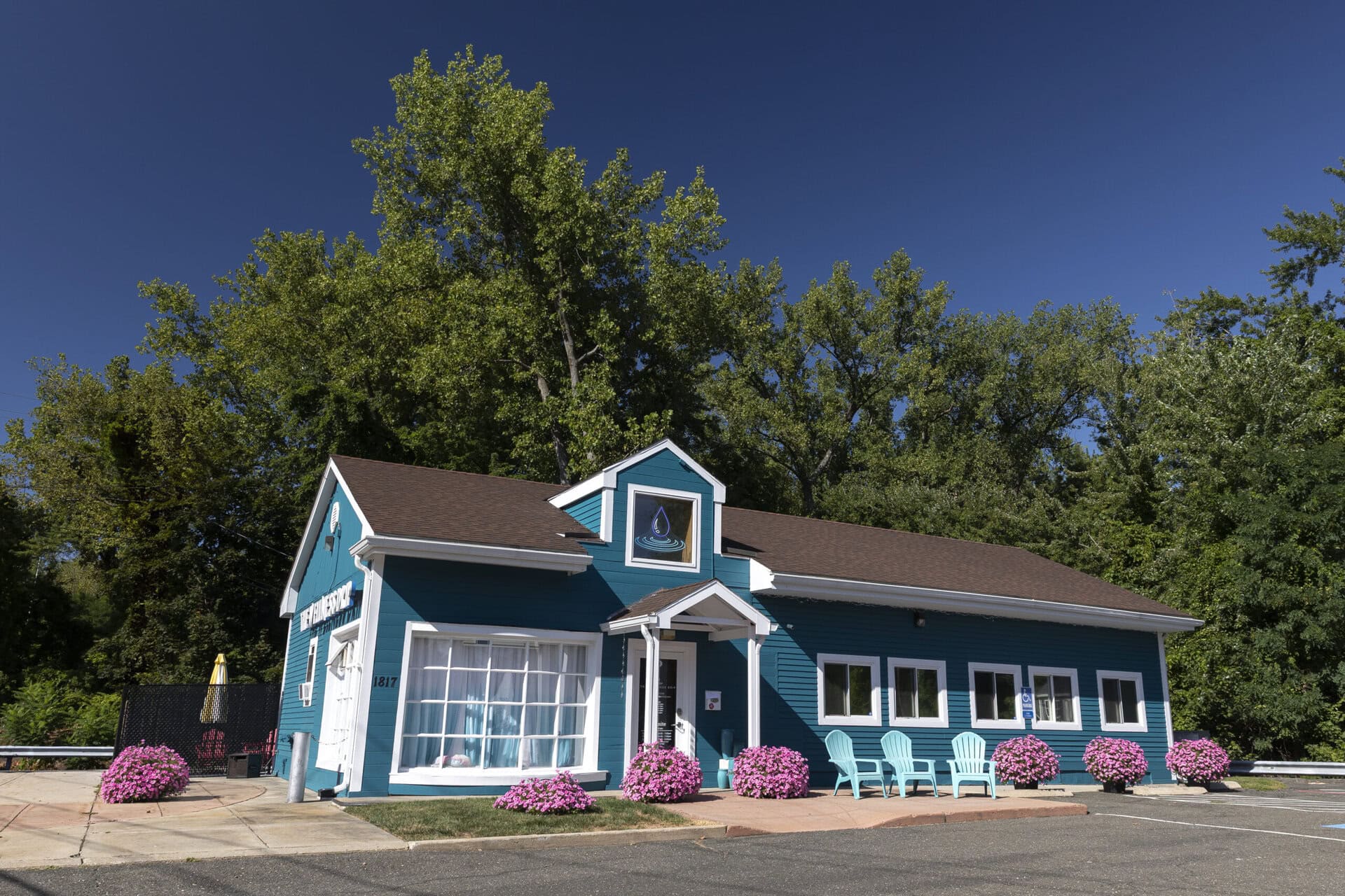 Bright blue wellness clinic with outdoor seating and pink flowers, offering IV therapy, hydration, and health wellness services in Holyoke, Massachusetts.