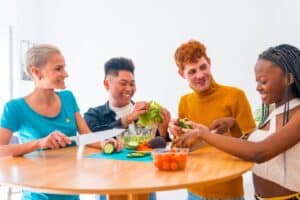 Group of diverse friends enjoying healthy food preparation with fresh vegetables, promoting wellness and healthy lifestyle choices.