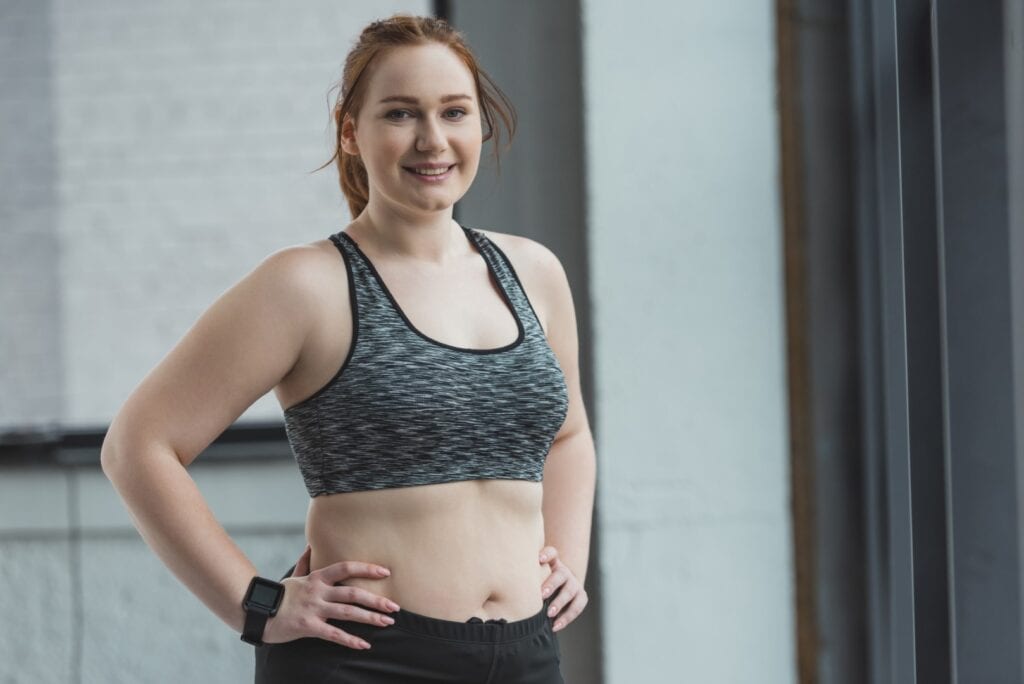 Smiling woman in workout attire at Wellness Drip Holyoke, showcasing confidence in non-invasive fat reduction treatments like HIFU and CoolSculpting. Non‑Invasive Fat Reduction for women